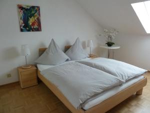 Schlafzimmer mit einem Bett mit weißer Bettwäsche und Kissen in der Unterkunft Apartmentvermietung Berg in Witten