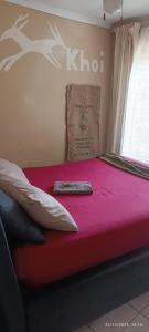 a bed with a pillow and a remote control on it at Bushman Spoor Backpackers in Soweto
