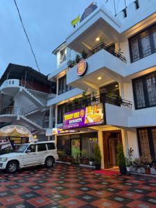 een witte truck geparkeerd voor een gebouw bij Thekkady Arasi Hotel in Thekkady