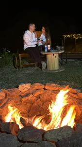 Un uomo e una donna seduti intorno a un focolare di Chalé Família Canto da Graúna a Ibicoara