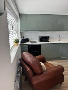 ein Wohnzimmer mit einer Ledercouch in einer Küche in der Unterkunft Modern & Cozy Studio Apartment in Andover in Andover