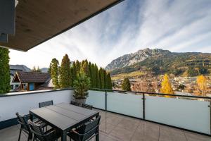a balcony with a table and chairs and mountains at Drei Berge Blick - by myNests in Gröbming