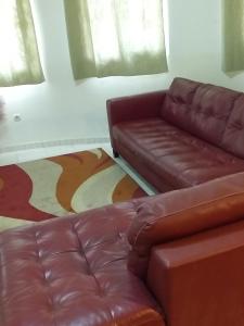 een woonkamer met een bruine leren bank en ramen bij Résidence Diamane Sokone in Sokone