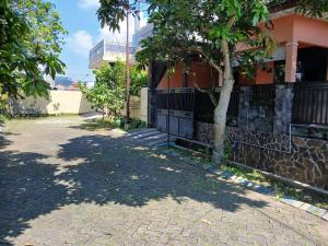 a tree on a sidewalk next to a house at Mangga in Sengkaling