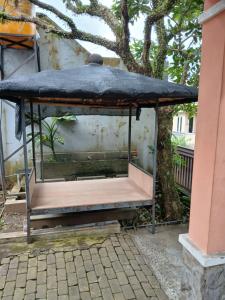 a bird cage sitting next to a tree at Mangga in Sengkaling