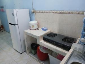 a kitchen with a stove and a white refrigerator at Mangga in Sengkaling