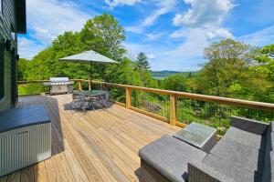 una terrazza in legno con tavolo e ombrellone di Timber Riverhouse a Readsboro