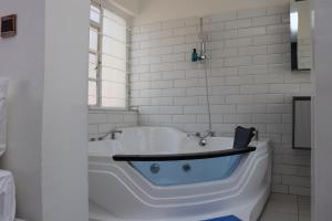 a bath tub in a white bathroom with a blueadder at Rio Eco Gardens Hotel in Nairobi +30 photos