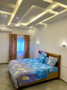 a bedroom with a bed with blue comforter and pillows at Résidence Prestige KGV Appt 201 in Douala