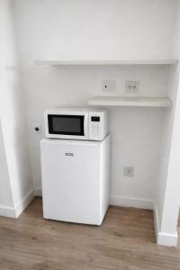 eine Mikrowelle auf einem Kühlschrank in einer Küche in der Unterkunft Studio Ilha Pura Barra Olímpica in Rio de Janeiro