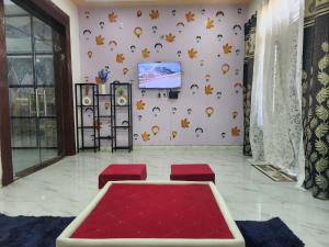 a room with a tv on a wall with red stools at Dks villa Homestay in Agra