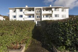 een wit gebouw met een heg ervoor bij 10 The Valley - Free Parking & WiFi, Close To Beaches in Porthcurno