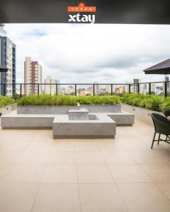 eine Terrasse mit zwei Bänken auf einem Gebäude in der Unterkunft Campos Sales by Xtay - Estúdio funcional e confortável a 25min do Teatro Positivo in Curitiba