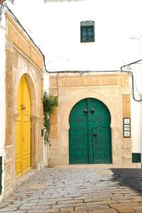 two green doors on a building with a cobblestone street at Palais Bayram Tunis in Tunis