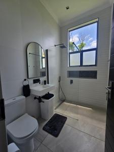 een badkamer met een toilet, een wastafel en een spiegel bij Maja Hzari in Densainagar