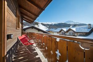 een rode stoel op een balkon met een besneeuwde berg op de achtergrond bij Hotel Crosal in Livigno
