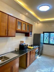 a kitchen with wooden cabinets and a stainless steel refrigerator at Résidence Prestige KGV Appt 201 in Douala