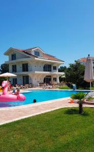 een groot huis met een groot zwembad met een roze opblaasbaar bed bij Resort Comfort Long Beach in Ulcinj