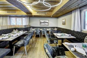 a dining room with tables and chairs and a chandelier at Hotel Unterhof in Filzmoos