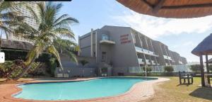a resort with a swimming pool in front of a building at Inyoni Rocks Cabanas 42 in Amanzimtoti