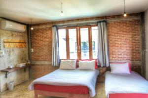 two beds in a room with a brick wall at Above The Sea Maesariang in Mae Sariang +34 photos