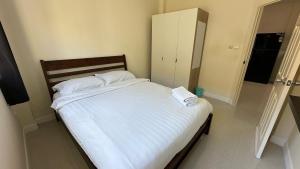 een slaapkamer met een bed met witte lakens en een kast bij Holiday home in Ban Na Khua