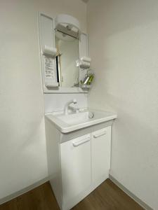 a white bathroom with a sink and a microwave at ホテル一休 in Otaru