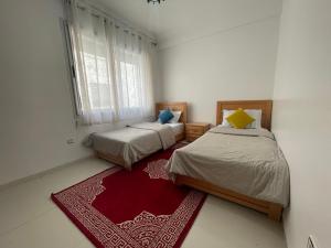 a bedroom with two beds and a red rug at Atlas Sunset Lodge in Agadir