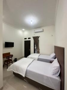 a hotel room with two beds and a desk at Nuwo Adin Syariah Guest House in Tanjungkarang