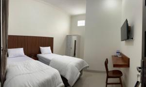 a hotel room with two beds and a chair at Nuwo Adin Syariah Guest House in Tanjungkarang