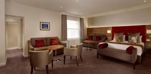 a hotel room with a bed and a couch and chairs at Norfolk Towers Paddington in London