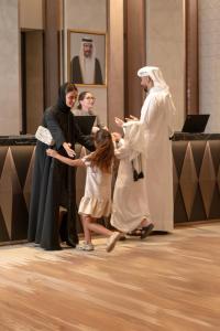 Park Hyatt Doha, Msheireb Downtown في الدوحة: فتاة صغيرة تقف بجانب البابا