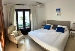 a bedroom with a large white bed and a chair at CuevaBlanca in Güime +16 photos