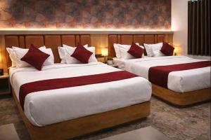 a bedroom with two beds with red and white pillows at The Sky Comfort Hotel Mahi in Dwarka +17 photos
