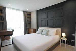 a bedroom with a white bed with a black wall at Modern Condo in Nimman 501 in Chiang Mai