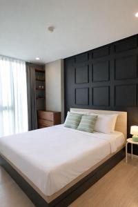 een slaapkamer met een groot wit bed met een zwart hoofdeinde bij Modern Condo in Nimman 501 in Chiang Mai