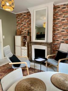 een woonkamer met stoelen en een open haard bij La Parenthèse Champenoise in Épernay