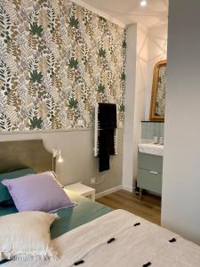 een slaapkamer met een bed en een muur met behang bij La Parenthèse Champenoise in Épernay