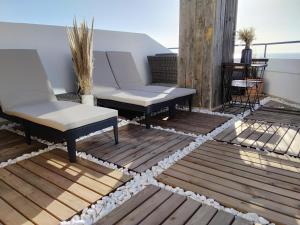 a patio with two chairs and a couch on a deck at LUXURY OCEAN PENTHOUSE- panoramic sea view & tikki bar on private terrasse in Luz