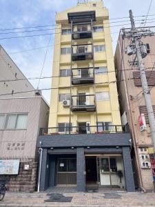 ein hohes gelbes Gebäude mit einem Balkon in der Unterkunft Katsu hotel 3号一室一厅 in Osaka