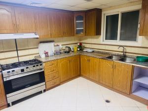 a kitchen with wooden cabinets and a stove and a sink at Sryia 1 in Sharjah