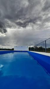 een groot blauw zwembad onder een bewolkte hemel bij Lucero de Brochero in Villa Cura Brochero