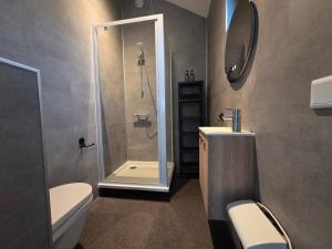 een badkamer met een douche, een toilet en een wastafel bij Chalet aan het water in Sprong +4 foto's