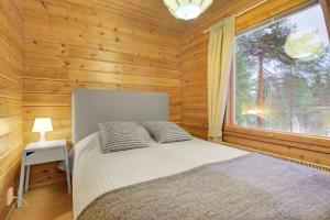 a bedroom with a bed and a large window at Pyhäkoti A - 30 Meters From the Slopes - Valkea Homes in Pyhätunturi