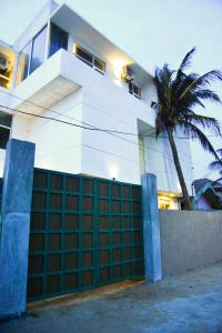 a white house with a fence and a palm tree at Ayurvedic Beach Resort in Negombo
