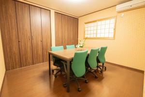 a conference room with a table and green chairs at 九洲別苑 in Osaka