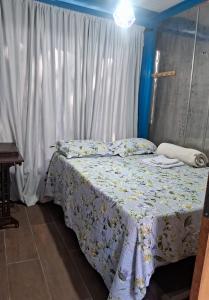 a bedroom with a bed with a flowered bedspread at Recanto da onça in Matinhos