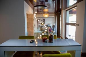 een eettafel met groene stoelen en een tafel met een mobiele telefoon bij Villa with Pool Bragadiru in Bragadiru