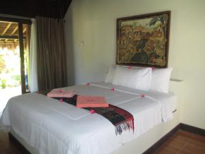 una camera da letto con un grande letto bianco con decorazioni rosse di Selong Belanak Bungalows a Selong Belanak