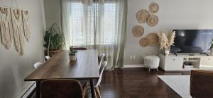 a living room with a dining room table and a television at Boho Retreat 3BD Condo Close to Ottawa in Gatineau